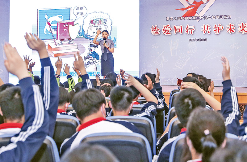 2021年5月30日,在新修訂的未成年人保護法和預防未成年人犯罪法即將正式施行之際,最高人民檢察院舉辦以“檢愛同行 共護未來”為主題的檢察開放日活動。圖為在開放日活動的法治教育課上,工作人員與學生互動。 新華社記者 殷剛/攝